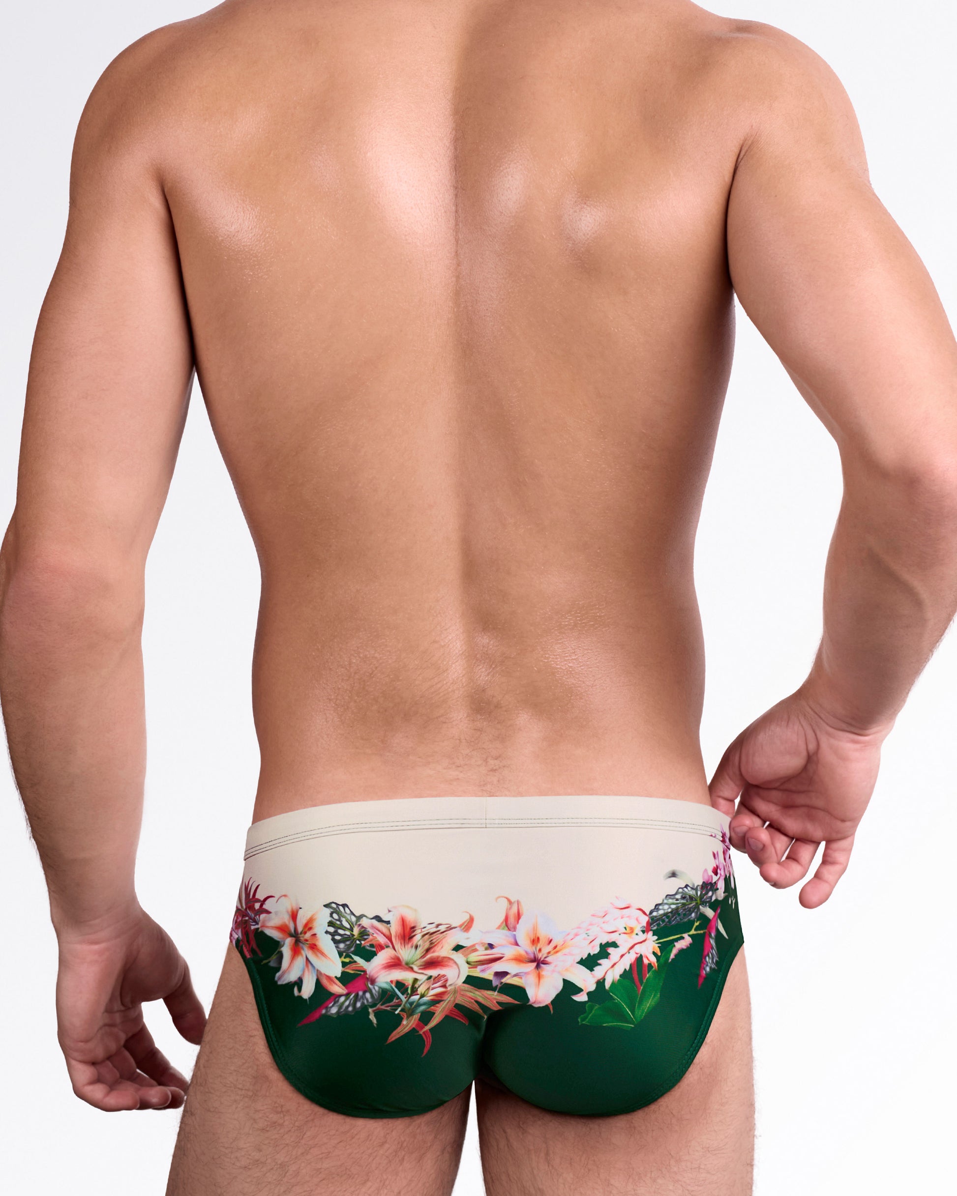 DC2 Bloom Service Swim Brief — back view showcasing wraparound botanical artwork with soft beige upper panel and rich green lower contrast.