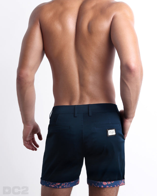 Back view of a model wearing woven twill cotton chino shorts in a dark blue color for men. These premium quality swimwear bottoms are DC2 by BANG! Clothes, a men’s beachwear brand from Miami.