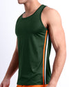 Male model wearing men’s BRAVE GREEN men’s Summer Tank Top in dark green color with stylish orange and red colored stripes. This high-quality shirt is by DC2, a men’s beachwear brand from Miami.