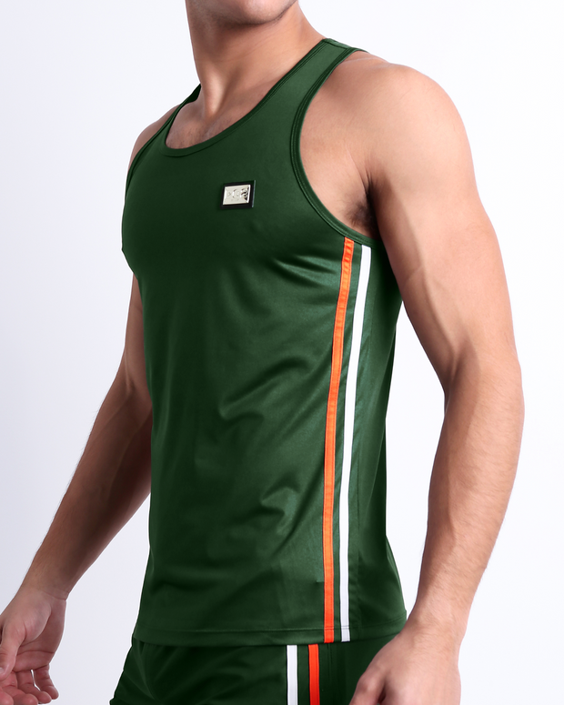 Male model wearing men’s BRAVE GREEN men’s Summer Tank Top in dark green color with stylish orange and red colored stripes. This high-quality shirt is by DC2, a men’s beachwear brand from Miami.