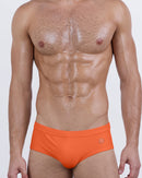 DC2 Spring/Summer 2025 collection — model wearing BRONZE FACTOR swim briefs, featuring a bold orange tone and sleek low-rise silhouette.