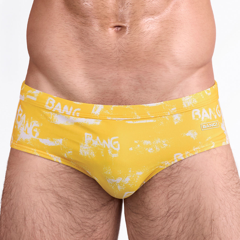 BANG Brush Rush Yellow Swim Brief — close-up front detail showcasing contoured pouch construction, smooth stretch swim fabric, and BANG logo plaque at hip.