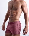 Side view of men’s shorter leg length shorts with dual pockets for men in a light purple wine color made by Miami based BANG! brand of men's beachwear.