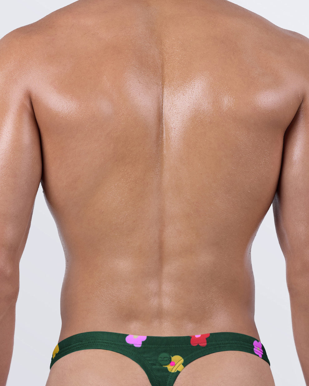 Back view of green men’s thong swimwear by DC2 Miami – T-back men's thong bathing suit with cheeky fit and bold flower print.