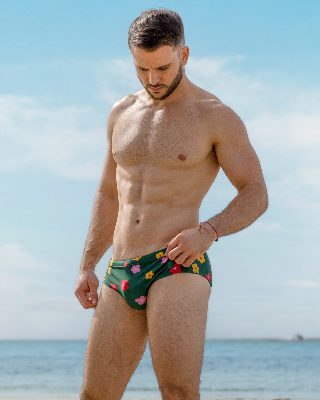 DC2 Buy Myself Flowers Swim Brief — model wearing dark green swim briefs with vibrant floral prints in pink, red, and yellow hues, crafted from quick-dry stretch fabric for a sleek and playful beach look.
