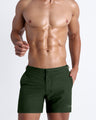 Male model wearing the ALPHA GREEN men’s swim tailored shorts in army green color by the Bang! brand of men's beachwear from Miami.