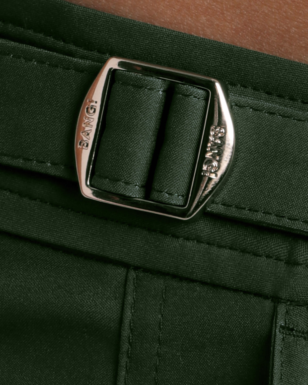Close-up view of the ALPHA GREEN men’s swimwear, showing custom branded golden adjustable side buckles.