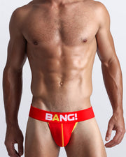 Front view of a sexy male model wearing a BANG! Cotton Jockstrap in BRAVO a solid red color with a red waist-band with the BANG! Logo offering a perfect fit. 