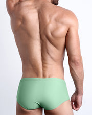 Back view of a male model wearing men’s CABANA GREEN Brazilian Sunga swimwear in a Pastel Spring Green color made with Italian-made Vita By Carvico Econyl Nylon by the Bang! Clothes brand of men's beachwear.