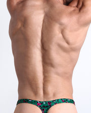 Back view of a Male model wearing beach swim bikini Swimsuit for men featuring a black, white, hot pink leopard animal print by the Bang! Clothes brand of men's beachwear.