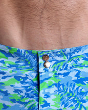 Close-up view of inseam and details of CAMO POP (BLUE/GREEN) swimsuit for men, showing custom branded golden buttons.