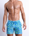 Male model wearing CAMO POP (BLUE/GREEN), a multicolor neon print for men. These premium quality swimwear bottoms are by BANG! Clothes, a men’s beachwear brand from Miami.