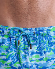 Close-up view of inseam and details of CAMO POP (BLUE/GREEN) swimsuit for men, with blue cord and custom branded golden cord-ends, and matching custom eyelet trims in gold.