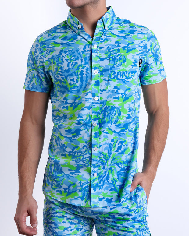 Male model wearing CAMO POP (BLUE/GREEN) men’s sleeveless stretch shirt and matching swimwear shorts, a multicolor neon print for men. This premium quality top is by BANG! Clothes, a men’s beachwear brand from Miami.