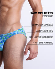 Infographic explaining the features of the CAMO POP (BLUE/GREEN) Swim Mini-Brief made by BANG! Clothes. These edgier cut mens swimsuit are minimal skin coverage, sculpts waistline, sits low for sexier look, and 4-way stretch fabric.