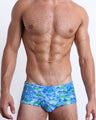 Front view of the CAMO POP (BLUE/GREEN) men’s Swim Sunga featuring a multicolor neon camo print, including shades of light blue, lime green, and blue colors. This premium quality swimwear is by BANG! Clothes, a men’s beachwear brand from Miami.