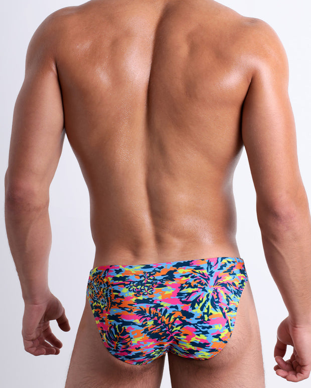 Back view of a model wearing CAMO POP (COLOR MIX) men’s beach mini-briefs featuring a colorful camo design, designed by BANG! Clothes in Miami.