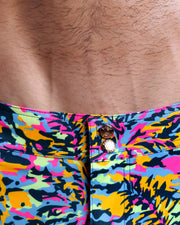 Close-up view of inseam and details of CAMO POP (NEON MIX) swimsuit for men, showing custom branded golden buttons.
