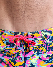 Close-up view of men’s summer Flex shorts by BANG! clothing brand, showing hot pink color cord with custom-branded golden cord ends, and matching custom eyelet trims in gold.
