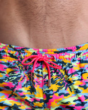 Close-up view of the CAMO POP (NEON MIX) men’s summer shorts, showing light blue cord with custom branded golden cord ends, and matching custom eyelet trims in gold.