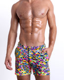 Male model wearing CAMO POP (NEON MIX) Tailored Shorts, a multicolor neon print for men. These premium quality swimwear bottoms are by BANG! Clothes, a men’s beachwear brand from Miami.