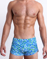 Front view of model wearing the CAMO POP (BLUE/GREEN) men’s Swim Shorts, premium swimwear featuring a multicolor neon camo print, including shades of light blue, lime green, and blue colors for men. These high-quality swimwear are by BANG!, a men’s beachwear brand from Miami.