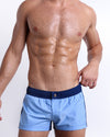 Male model wearing CASINO ROYALE (BLUE) square leg swim shorts, premium swimwear with a stylish color block design in dark blue and light blue for men. These high-quality swimwear bottoms by BANG! Clothes, a men’s beachwear brand from Miami, is inspired by the iconic style of Daniel Craig's blue swim trunks in the 2006 film Casino Royale.