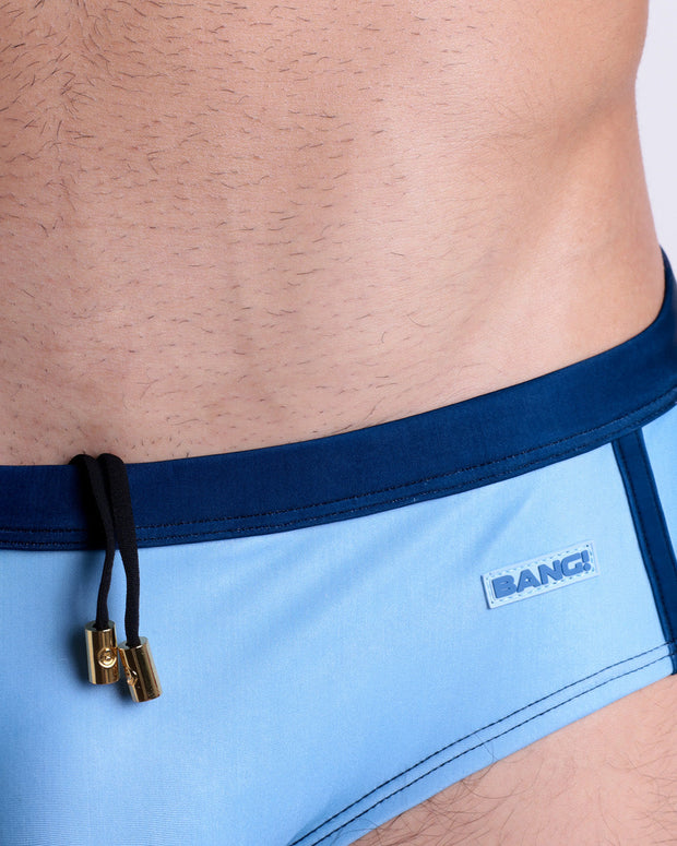 Close-up view of the CASINO ROYALE (BLUE) men’s drawstring briefs showing black cord with custom branded golden cord ends, and matching custom eyelet trims in gold.