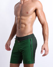 Side view of the CASINO ROYALE (GREEN) for men’s summer long boardshorts with dual zippered pockets. Inspired by actor Daniel Craig's iconic green swim trunks worn in the 2006 film Casino Royale, these shorts were designed by BANG! Clothes in Miami.