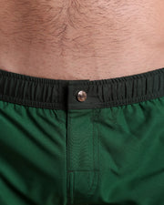 Close-up view of the CASINO ROYALE (GREEN) men’s Mini shorts, showing custom branded metal button in gold by Bang!