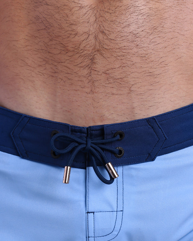 Close-up view of men’s summer Flex shorts by BANG! clothing brand, showing blue color cord with custom-branded golden cord ends, and matching custom eyelet trims in gold.