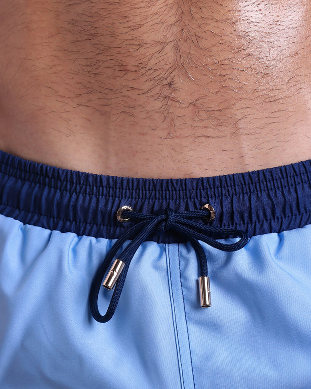 Close-up view of inseam and details of CASINO ROYALE (BLUE) swimsuit for men, with dark blue navy cord and custom branded golden cord-ends, and matching custom eyelet trims in gold. 