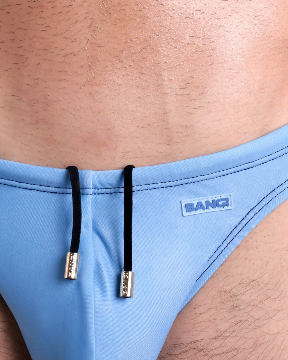 Close-up view of the CASINO ROYALE (BLUE) men’s drawstring briefs showing black cord with custom branded golden cord ends, and matching custom eyelet trims in gold.