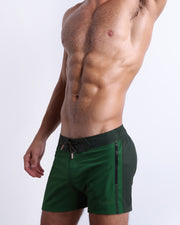 Side view of the CASINO ROYALE (GREEN) for men’s summer Flex Shorts with dual zippered pockets in a color block green colors. Inspired by actor Daniel Craig's iconic blue swim trunks worn in the 2006 film Casino Royale, these shorts were designed by BANG! Clothes in Miami.