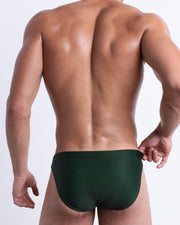 Back view of a model wearing CASINO ROYALE (GREEN) men’s beach brief in light green and dark green color. Inspired by actor Daniel Craig's iconic blue swim trunks worn in the 2006 film Casino Royale, is designed by BANG! Clothes in Miami.