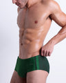 Side view of muscular male model wearing CASINO ROYALE (GREEN) Summer swim Brazilian sunga swimsuit for the beach with a stylish color block design in green colors for men. This high-quality brief is by BANG! Clothes, a men’s beachwear brand from Miami. Inspired by the iconic style of Daniel Craig's blue swim trunks in the 2006 film Casino Royale.