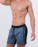 A male model wearing the CASINO ROYALE (GREY) - Resort Shorts by DC2 Miami. These premium shorts feature a sleek grey body with a black waistband, drawstring fastening, and deep side pockets for a stylish and functional look.