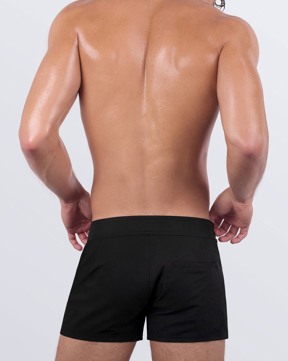 Back view of a male model showcasing the CASINO ROYALE (LEOPARD + BLACK) Beach Shorts by BANG! Miami. These tailored beach shorts feature a minimalist back pocket design, a seamless navy blue waistband, and a comfortable stretch fabric for unrestricted movement.