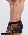 Side view of a male model in the CASINO ROYALE (LEOPARD + BLACK) Show Shorts by BANG! Miami. These trendy show shorts are designed with deep slip pockets, water-resistant fabric, and a contoured fit, perfect for beach days, pool parties, and resort lounging.
