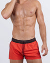 Frontal view of a male model wearing the CASINO ROYALE (RED) Show Shorts for men by BANG! Miami. These bold, modern-fit swim shorts feature a striking red front with black side panels, an elastic waistband with an adjustable drawstring, and deep slip pockets.