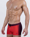Side front view of the CASINO ROYALE Swim Trunks in Red – bold red front with deep burgundy side panels and waistband, finished with a black drawstring.