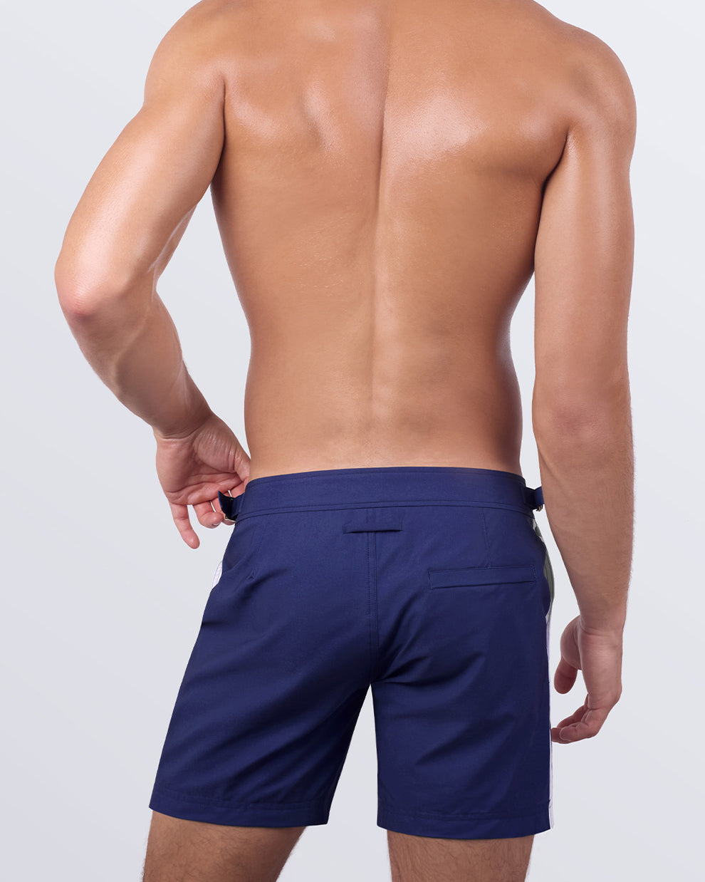 Back view of a male model in the Casino Royale (White + Navy Blue) Tailored Shorts. These premium beach shorts showcase a fitted silhouette, a functional back pocket, and a refined tailored cut designed for a sharp, polished beachwear style.