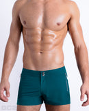 Front view of a male model wearing the men’s CHIC TEAL Beach Shorts, in a dark teal color for men. These premium quality swimwear bottoms are by DC2 a capsule brand from BANG! Clothes, a men’s beachwear brand from Miami.