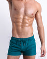 Male model wearing CHIC TEAL swimming Poolside Shorts, in a solid vibrant teal color for men. These premium quality swimwear bottoms are by DC2, a men’s beachwear brand from Miami.