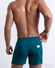 Back view of the CHIC TEAL beach Resort Shorts in a solid dark teal color, complete with a back pocket, designed by DC2 a capsule brand by BANG! Clothes based in Miami.