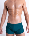 Front view of model wearing the CHIC TEAL men’s swimming bottoms in a solid dark teal color by DC2, a men's beachwear brand from Miami.