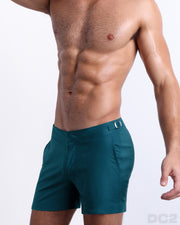 Side view of the CHIC TEAL swimsuit Tailored Shorts with dual pockets and adjustable side buckles for men featuring a teal color is designed by BANG! Clothes in Miami.