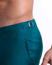Close-up view of the CHIC TEAL men’s swimwear, showing custom branded silver metal adjustable side buckles.