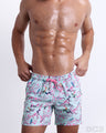 Male model wearing the CLOSE TO YOU Resort Shorts, premium swimwear with a stylish exotic birds design in a light blue color with pink flowers for men. These high-quality swimwear bottoms by DC2, a men’s beachwear brand from Miami.