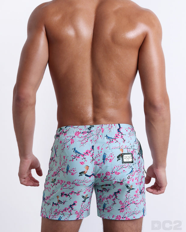 Back view of the CLOSE TO YOU beach Resort Shorts with dual pockets in a light blue color with an exotic birds print, complete with a back pocket, designed by DC2.